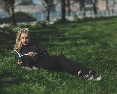 倚在草地上看书的女人